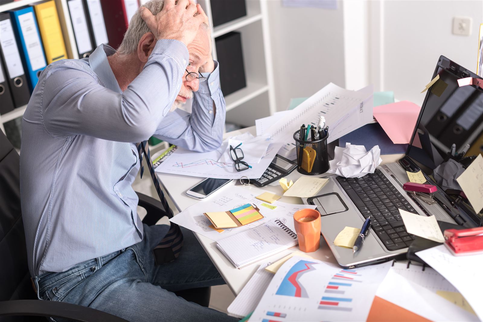 A business owner overwhelmed at his desk, head in hands